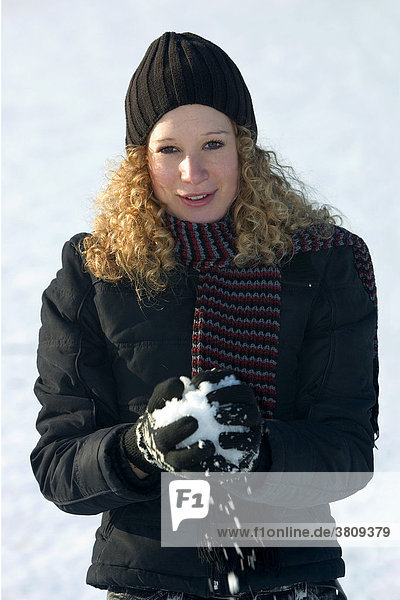 A young woman forming a snowball