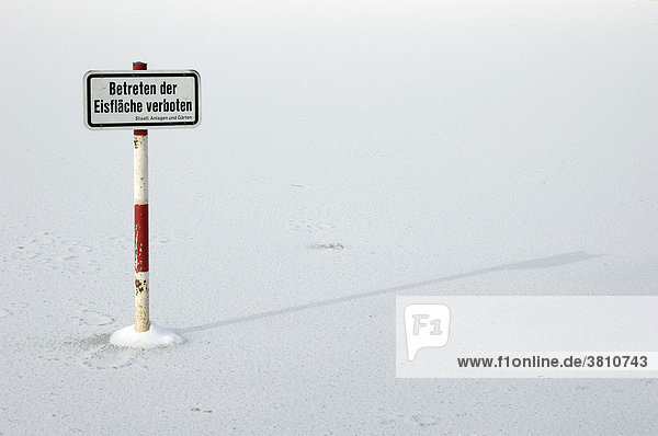 Zugefrorener Teich mit Schild Betreten der Eisfläche verboten