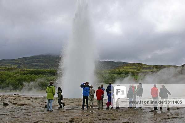 Tourists looking at the geyser Strokkur in Iceland