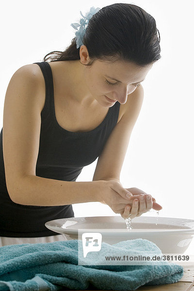 Junge Frau schöpft Wasser aus einer Waschschüssel