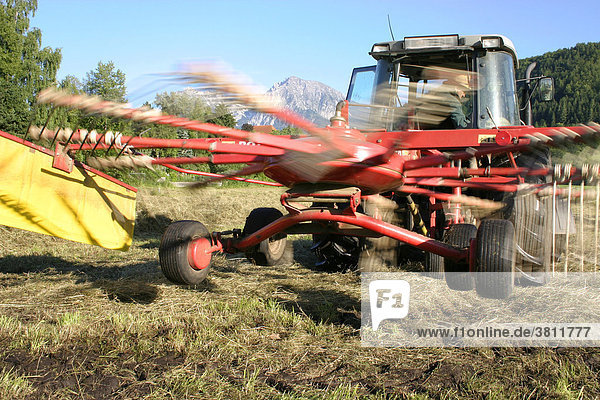 Red tractor with rotating hay rake (motion blur)