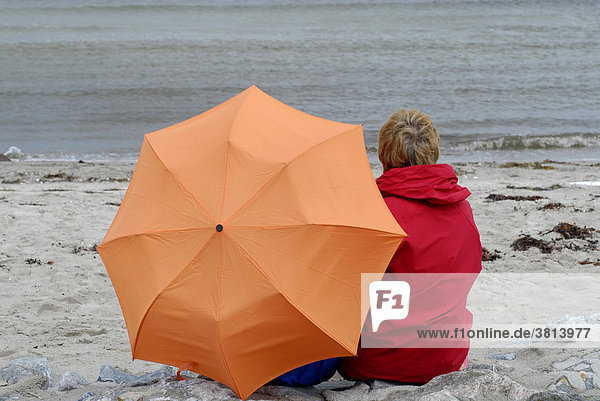 Personen sitzen mit regenschirm am strand