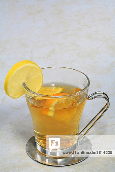 Eine Tasse Tee mit Orangenstücken und einer Scheibe Zitrone