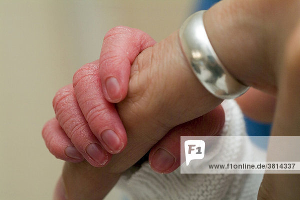 Hand eines Neugeborenen greift nach dem Finger der Mutter
