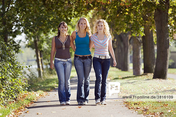 Three young women walking through a park