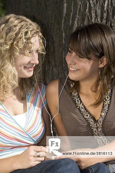 Zwei Freundinnen hören gemeinsam Musik mit nur einem MP3-Player