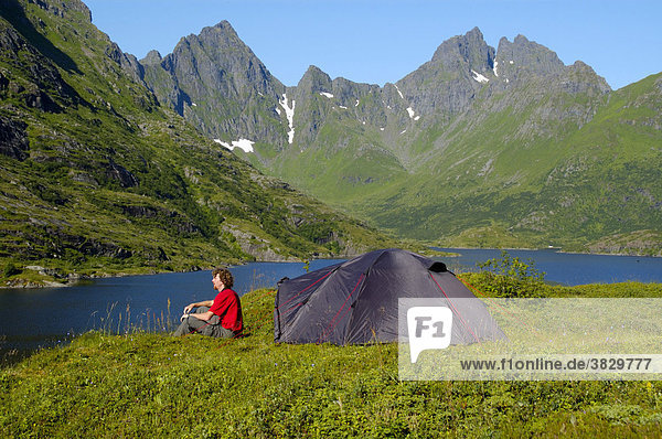 MR Junger Mann sitzt vor seinem Zelt in der Wildnis von Moskenesöy mit Agvatnet und Mannen Lofoten Norwegen