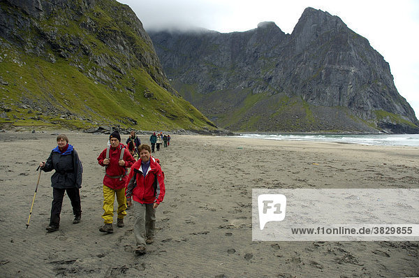 MR Group of hikers on a sandy beach Kvalvika Bay Moskenesoya Lofoten Norway