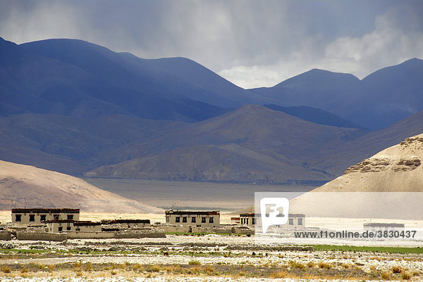 Licht und Schatten flache Häuser vor hohen Bergen bei Lungchang Tibet China
