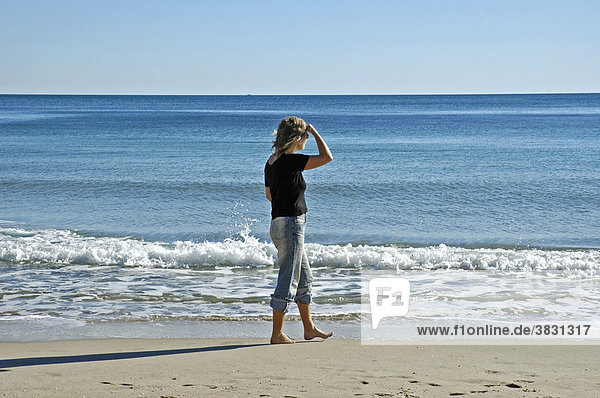 Frau in Jeans schaut in die Ferne am Strand  30 - 40 Jahre  40 - 45 Jahre  Mittelmeer  Costa Blanca  Spanien