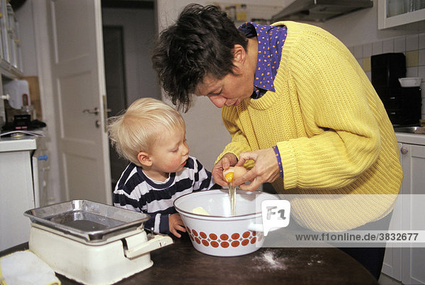 Mother and little Boy putting egg in dough