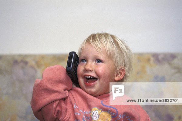 Zweijähriger Bub telefoniert mit Fernseh-Fernbedienung