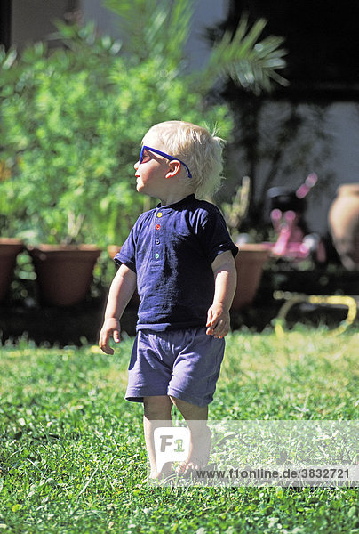 Two-year-old boy with shades in the garden MR