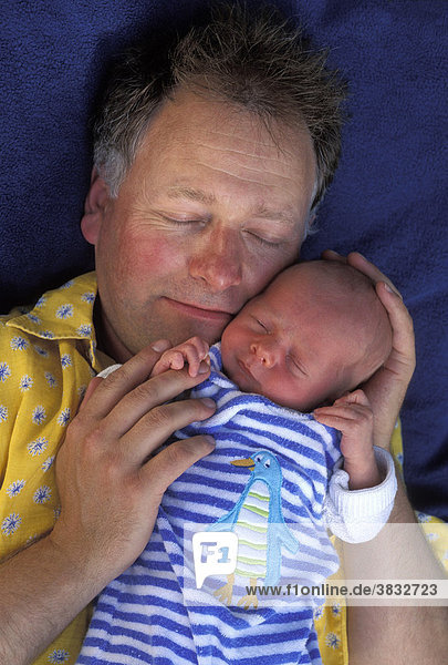 Vater schläft neben Neugeborenem