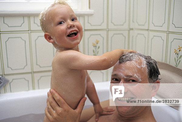 Zweijähriger Junge und Vater waschen in der Wanne die Haare