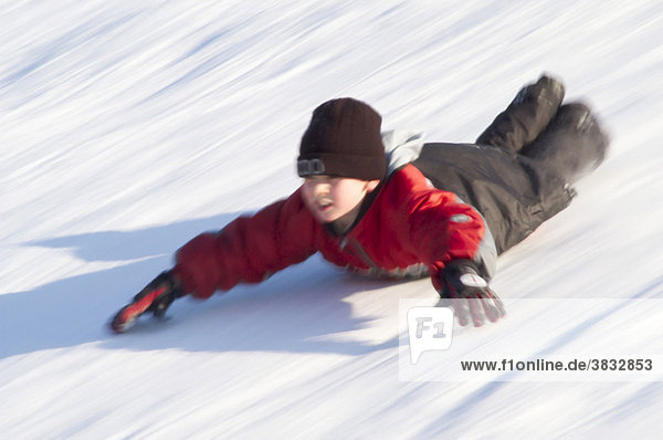 Boy sliding on his belly downhill