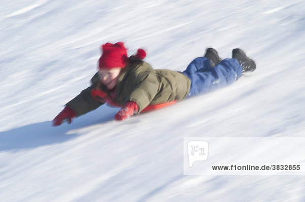 Girl sliding on her belly downhill