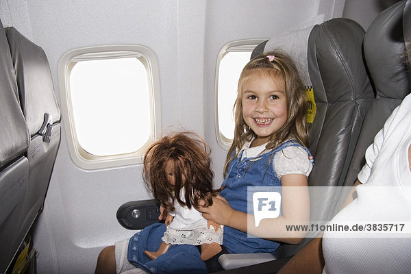 Kleines Mädchen mit Puppe in Flugzeug