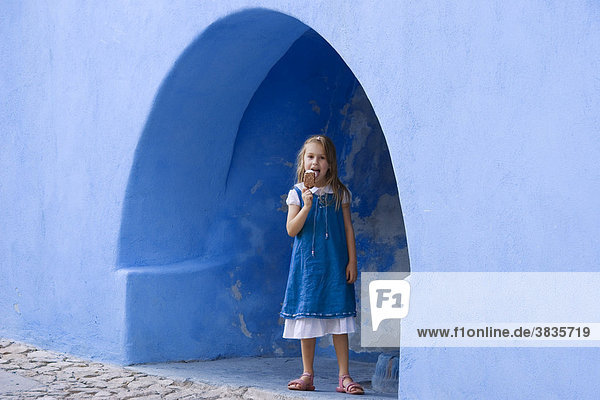 Girl eating icecream  blue house in Posada  Sardinia  Italy