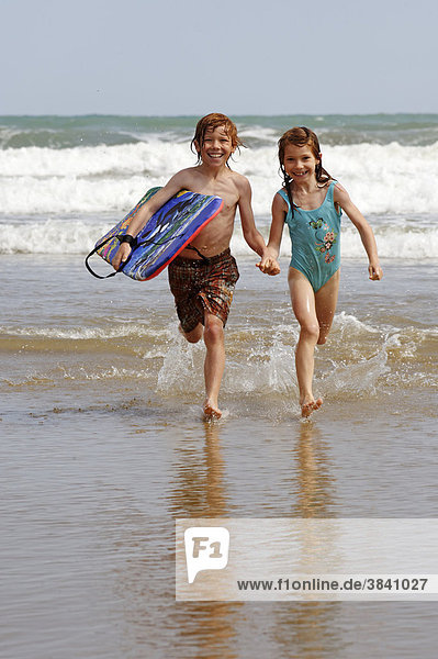 Kinder mit Boogyboard und Wellen am Strand  Meer