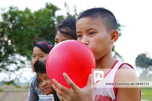Junge bläst einen roten Luftballon auf  Kinderheim Margaritha  Marihat  Batak Region  Sumatra  Indonesien  Asien