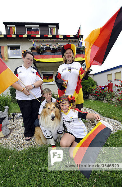 Fans der deutschen Nationalmannschaft in Nationaltrikots mit Deutschlandflaggen vor geschmücktem Wohnhaus  Stuttgart  Baden-Württemberg  Deutschland  Europa