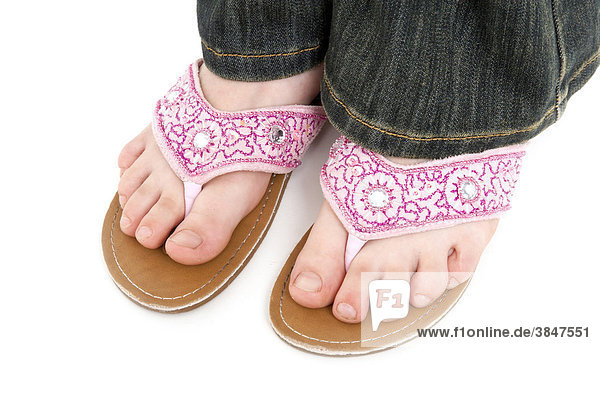 Füße eines Mädchens mit rosafarbenen Sandalen