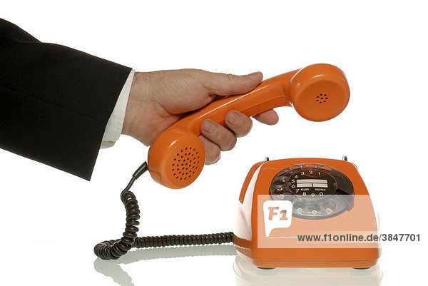 Businessmann hält Hörer eines orangefarbenen Telefons