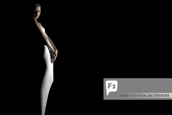 Junge Frau in weißem Kleid umrahmt von Licht und Schatten  Fashion