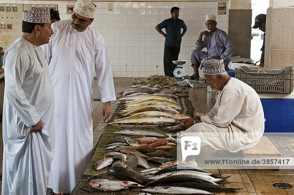 Zwei männliche Omani bei einem Fischverkäufer auf dem Fischmarkt in Mutrah  Oman  Naher Osten