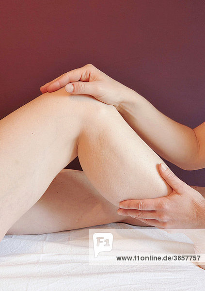 Hände einer Therapeutin behandeln das Kniegelenk einer jungen Frau  Heilmassage
