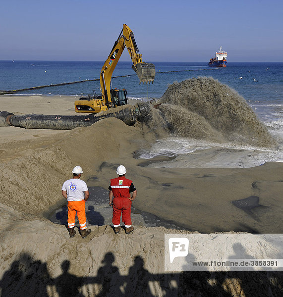 Onlookers watching while a dredger is pumping sand through a hose onto a beach for beach nourishment or beach replenishment  Platja de Barceloneta  Barcelona  Catalonia  Spain  Europe