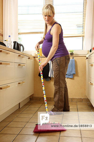 Schwangere Frau  9. Monat  zuhause  bei der leichten Hausarbeit  Küche putzen