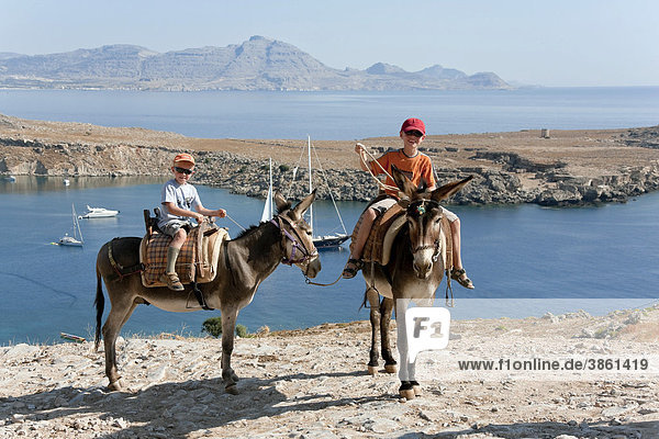 Two children riding donkeys  near Lindos  Rhodes  Dodecanese  Greece  Europe