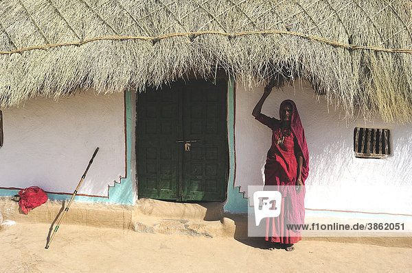 Frau im Sari am Eingang zu ihrem Wohnhaus mit vernähtem Reisigdach  Wüste Thar  Rajasthan  Nordindien  Indien  Asien