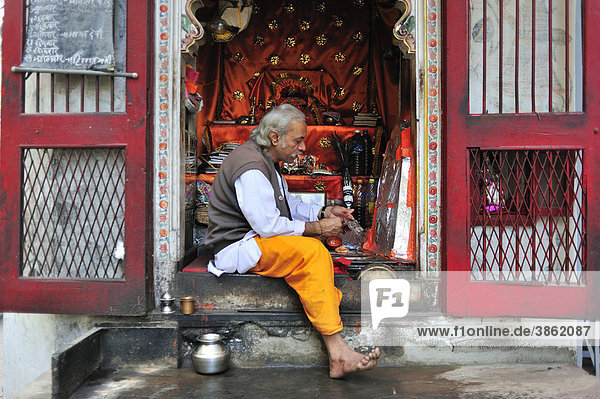 Ein Brahmane beklebt in einem kleinen hinduistischen Tempel eine Gottheit mit Alufolie  Udaipur  Rajasthan  Indien  Asien
