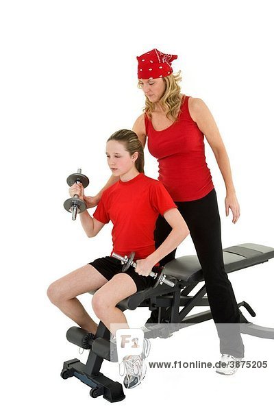 Caucasian mother helping her preteen daughter to lift weights using a dumbbell on a white background