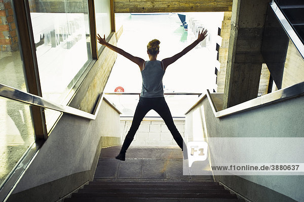 Teenagerin im Treppenhaus  Springen in der Luft  Rückansicht