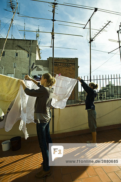 Schwestern hängen Wäsche zum Trocknen auf dem Dach Wäscheleine
