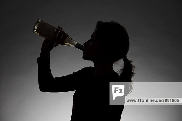 Frau trinkt aus einer Alkoholflasche  Symbolbild Alkoholmissbrauch  Drogensucht