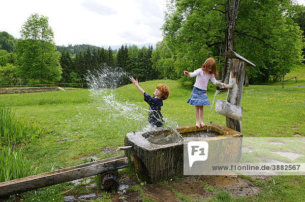 Children are playing with water at a fountain