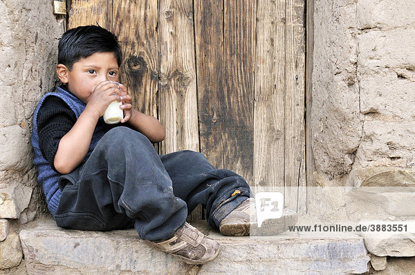 A boy leaning against a wall with a glass of milk  Bolivian Altiplano highlands  Departamento Oruro  Bolivia  South America