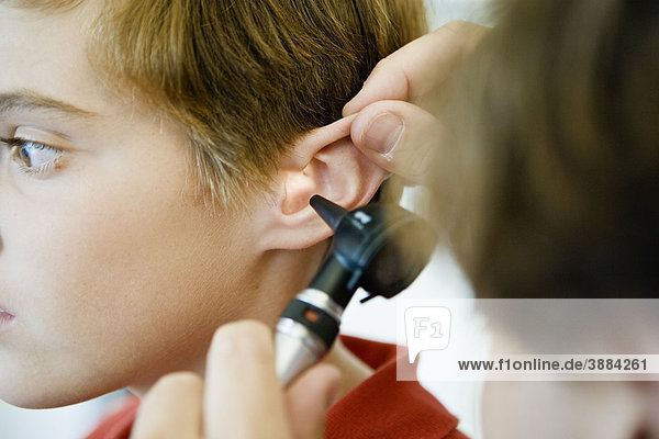 Examining young patient's ear with otoscope
