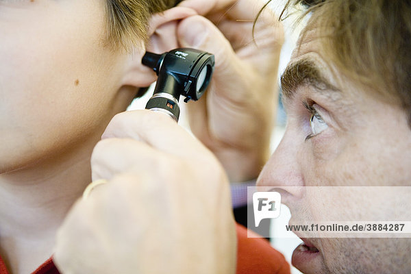 Doctor examining patient's ear with otoscope