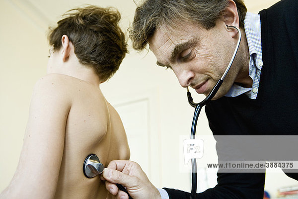Doctor examining young patient  using stethoscope