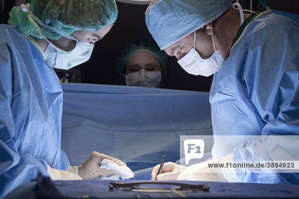 Krankenschwester  die den Chirurgen während der Operation unterstützt