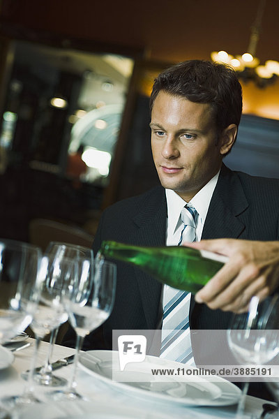 Mann im feinen Restaurant  der zusieht  wie der Kellner Wein ausschenkt.