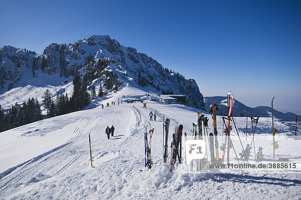 Blick von der Sonnenalm zur Bergstation der Kampenwandbahn  hinten die Scheibenwand  vorne Skier im Schnee  dahinter Spaziergänger auf dem Weg zur Seilbahn  Chiemgau  Bayern  Deutschland  Europa