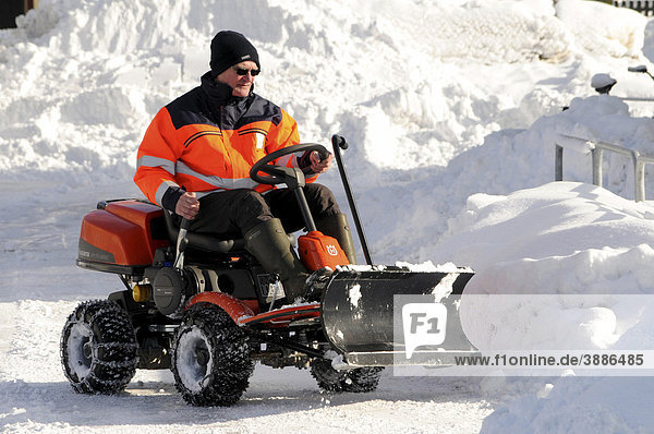 Mann mit Mini-Traktor bei der Schneeräumung in Schweden  Skandinavien  Europa