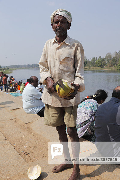 Mann schneidet Kokosnuss  Kapila  Kabini  Kabbani Fluss  Nanjangud  Karnataka  Südindien  Indien  Südasien  Asien